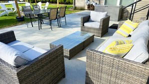 A patio with wicker furniture, a table, and chairs.
