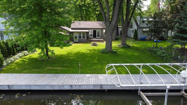 A house with a front yard, a dock, and a small body of water.