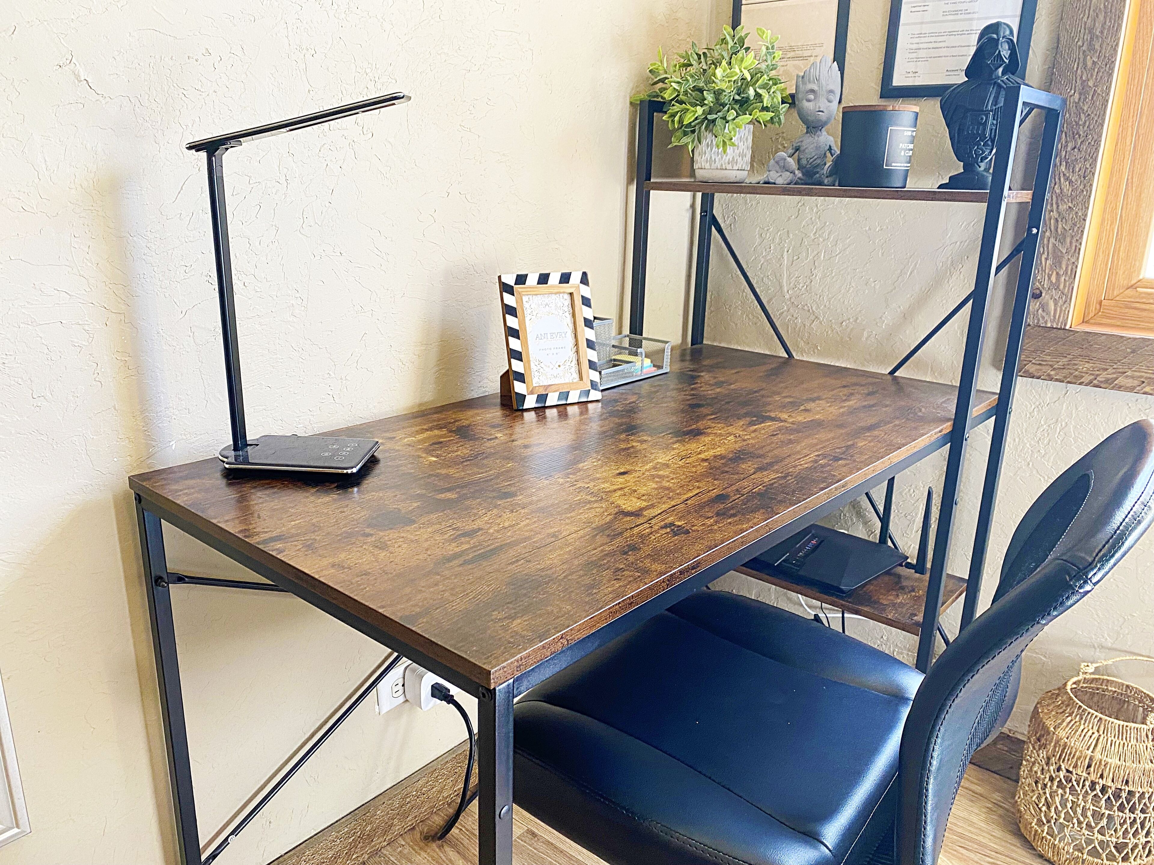 A wooden desk with a laptop, a picture frame, and a plant on a shelf.