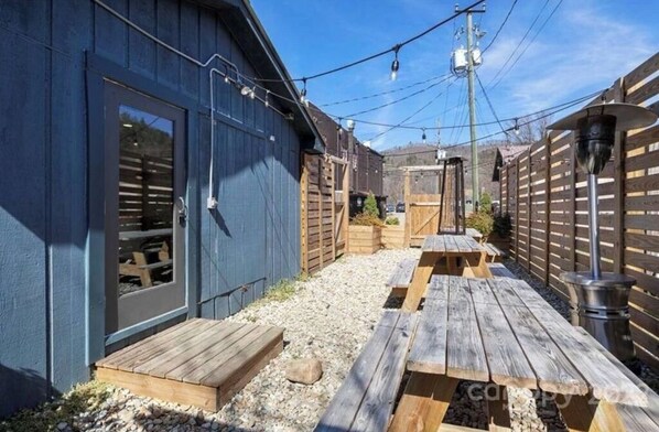 Relax on the deck with benches, surrounded by a wooden fence and a covered entrance.