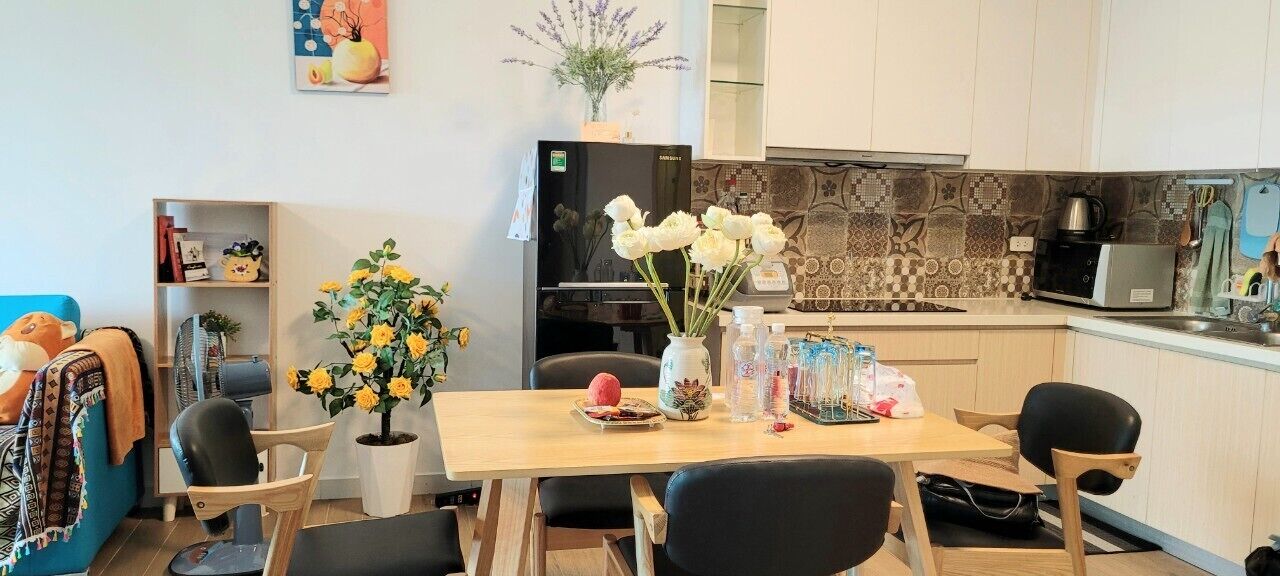 A modern kitchen with a dining table, chairs, and a refrigerator.