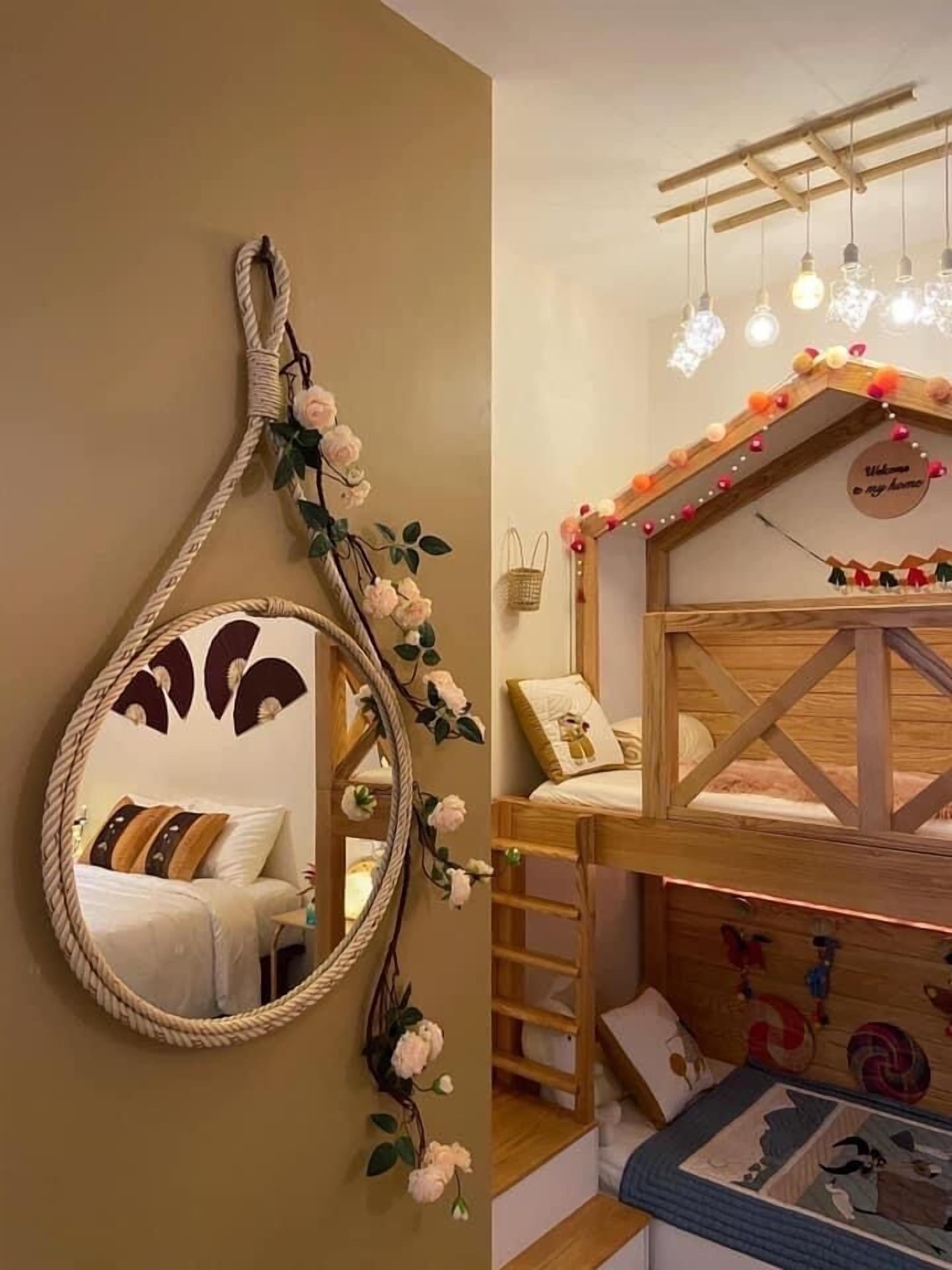 Una habitación infantil con una cama litera, un espejo colgante con adornos florales y un cartel de bienvenida.