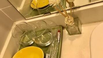 A bathroom with a mirror, a yellow bowl, a toothbrush, and a glass container.