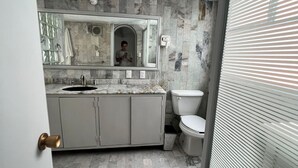 A bathroom with a marble floor, a sink, a toilet, and a mirror. - beautiful apartment in polanco (Ciudad de México)