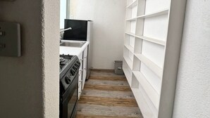 A narrow kitchen with white cabinetry, a stove, and a window. - beautiful apartment in polanco (Ciudad de México)