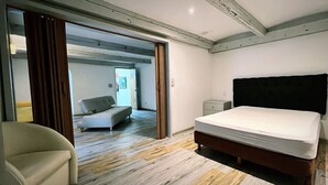 A bedroom with a bed, a chair, and a sofa. There is a door leading to another room. - beautiful apartment in polanco (Ciudad de México)