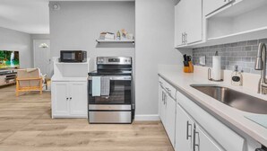 Una cocina moderna con armarios blancos, electrodomésticos de acero inoxidable y piso de madera.