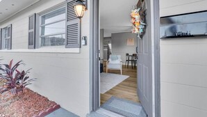 Fachada moderna de una casa con buzón, un porche con banca y un pequeño jardín.