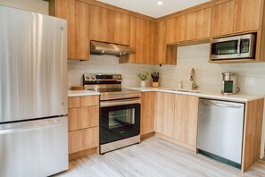A modern kitchen with wooden cabinets, stainless steel appliances, and a dishwasher.