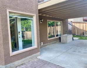A house with a covered patio, large windows, and a concrete floor.