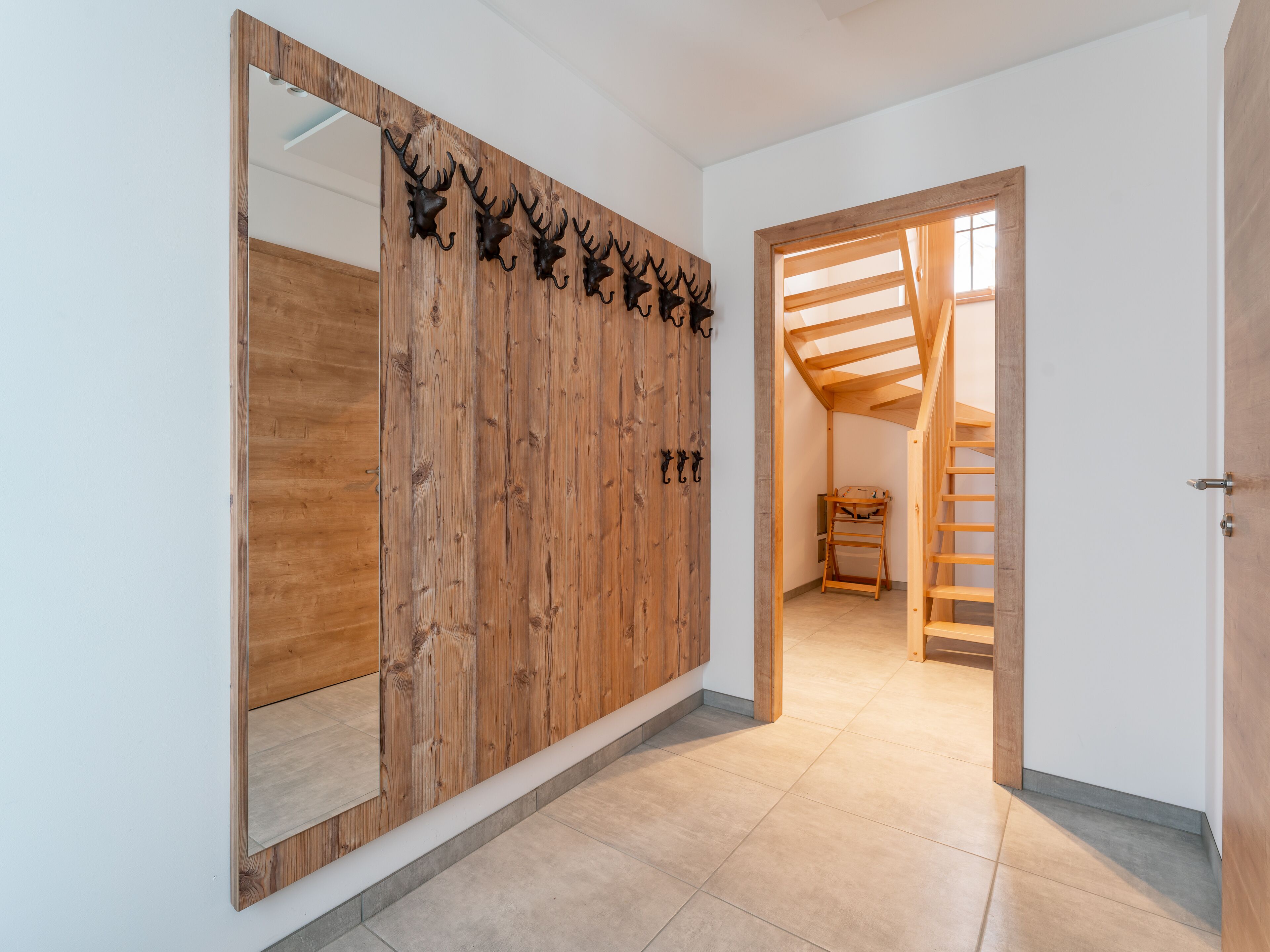 Un couloir avec une armoire en bois, un miroir et un escalier en bois.