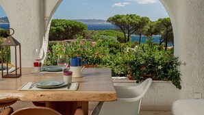 Un espace extérieur aménagé pour prendre les repas, avec vue sur la mer et les collines.