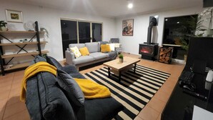 Een woonkamer met een bank, een salontafel, een open haard en een bureau.