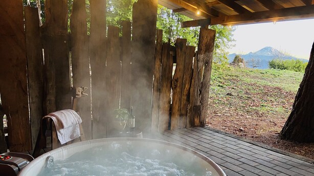 Un bain à remous avec une terrasse en bois et une vue sur les montagnes.