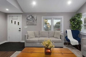 A living room with a grey sofa, a wooden coffee table, a blue armchair, and a plant.