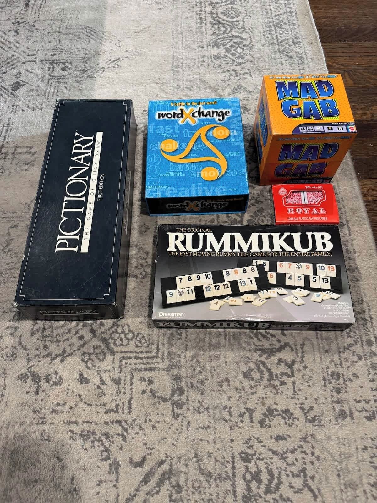 Uma mesa de jogos com quatro jogos de tabuleiro: Pictionary, WordXchange, Mad Gab e Rummikub.