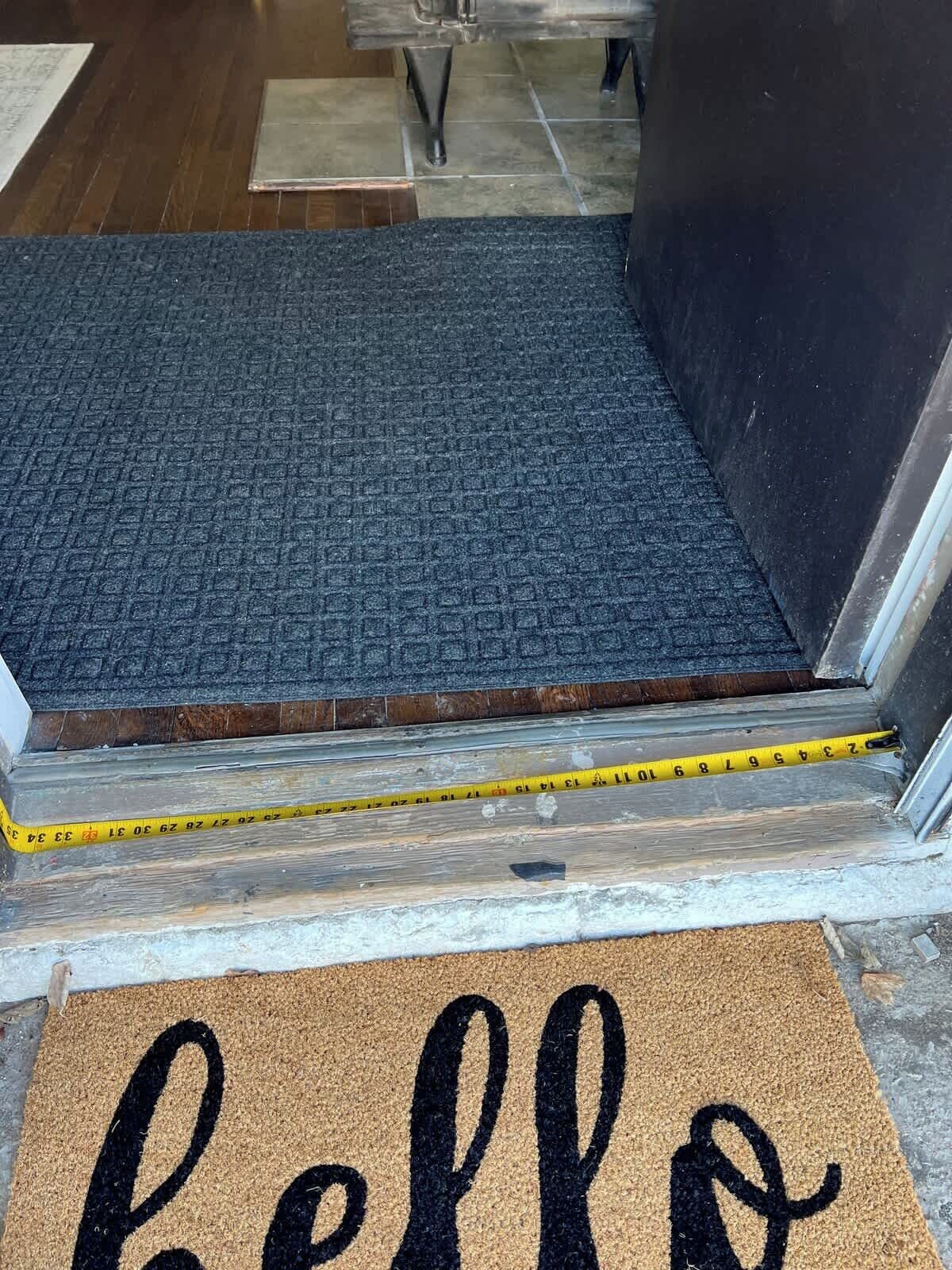 A carpeted entrance with a measuring tape, a doormat with 'hello' text, and a tiled floor.