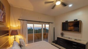 A bedroom with a bed, a TV, a balcony with curtains, and a ceiling fan. - Quinta with ocean and golf course panoramic views (La Paz)