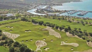 A golf course with bunkers, a marina, and a large building in the background. - Quinta with ocean and golf course panoramic views (La Paz)