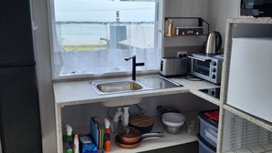 Une cuisine compacte avec une fenêtre, un grille-pain, une bouilloire et des étagères de rangement.