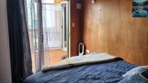 Une chambre à coucher avec un lit, un mur en bois, une fenêtre avec des rideaux et une vue sur l’extérieur.