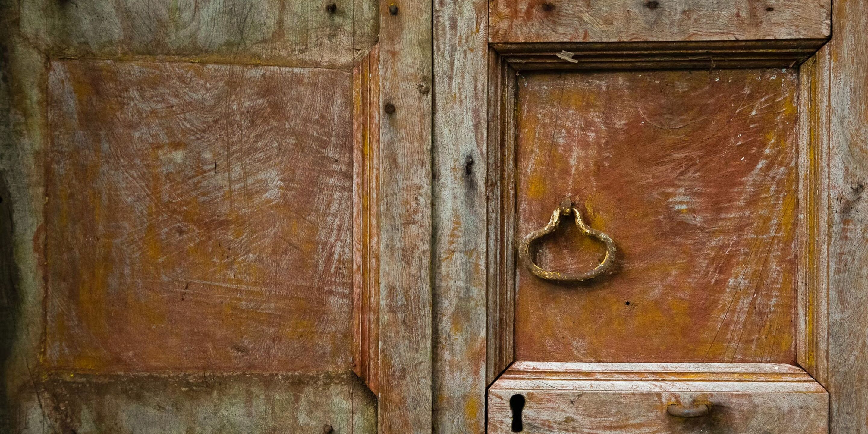 A wooden door with a brass ring handle and a keyhole.
