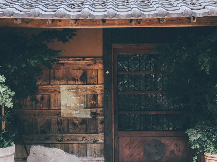A wooden door with a frosted glass panel, flanked by potted plants.