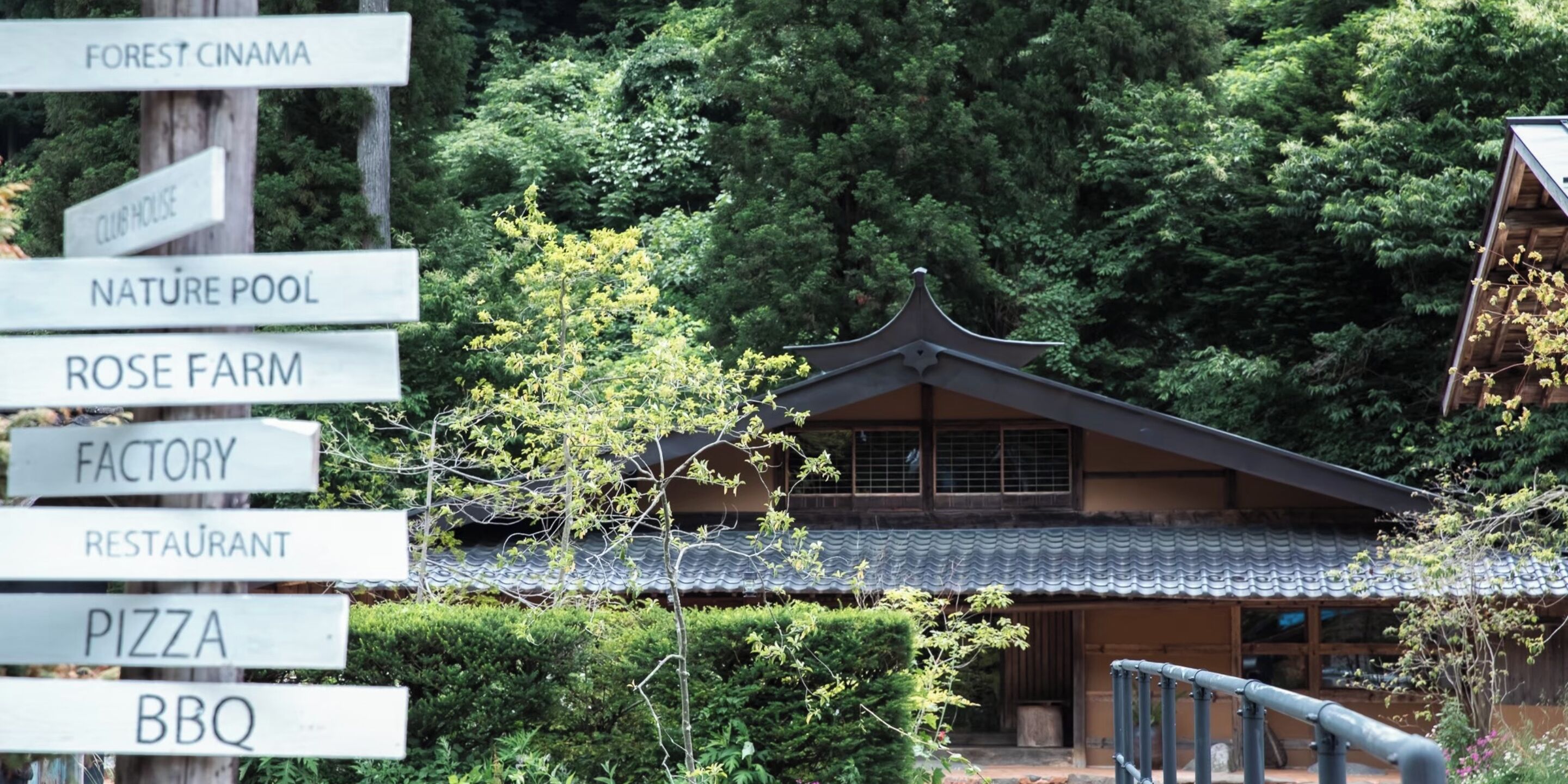 A traditional Japanese building with a tiled roof, surrounded by lush greenery.