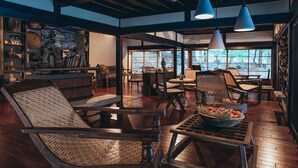 A spacious room with wooden flooring, a dining area with chairs and tables, and large windows offering a view of the outdoors. - La Terra Nagano (Shiojiri)