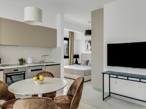 A modern kitchen with a dining area, a flat-screen TV, and a sofa.