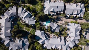 Vista aérea de una zona residencial con varias casas que presentan techos angulares y distintivos, y una piscina central.