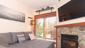 Una sala de estar con sofá, chimenea y un cuadro de un paisaje urbano.