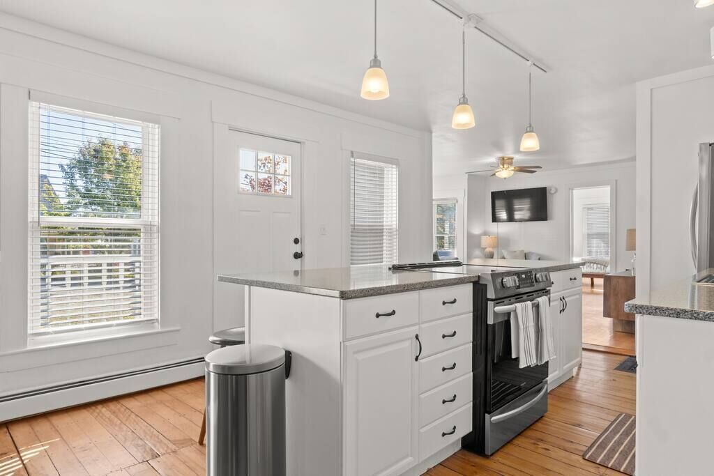 A modern kitchen with white cabinetry, a central island, and pendant lighting.
