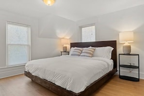 A bedroom with a large bed, two bedside tables, and a ceiling light fixture. - Spacious 9-BR Downtown Residence 3-Min to Okemo (Ludlow)