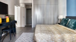 Ein Schlafzimmer mit Bett, Schreibtisch, Stuhl, Fernseher und Kleiderschrank.