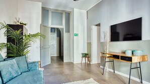 Ein modernes Wohnzimmer mit einer Couch, einem Holztisch, einem Fernseher und einer Pflanze.