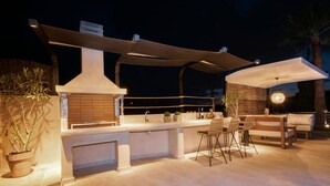 An outdoor bar area with a large countertop, bar stools, and a pergola providing shade. - Heated pool, kids pool, gorge and sea views! (Rethymno)
