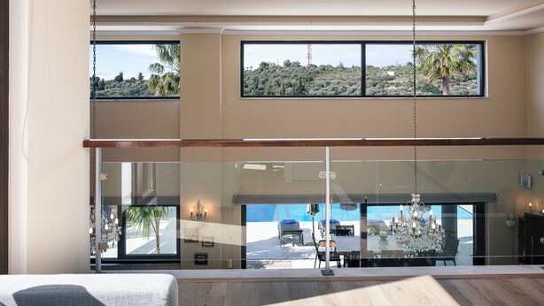 A modern interior with large windows, a chandelier, and a view of a vehicle outside. - Heated pool, kids pool, gorge and sea views! (Rethymno)