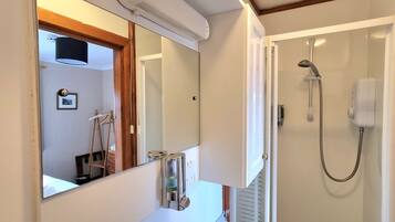 Un baño con un espejo grande, ducha y radiador.