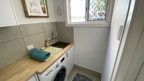 Une cuisine compacte équipée d’un lave-linge intégré, d’un évier et d’une fenêtre donnant sur un beau paysage.