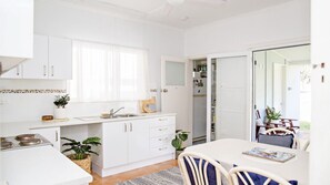 Une cuisine moderne avec des meubles blancs, un coin repas comprenant une table et des chaises, et une porte-fenêtre coulissante donnant sur un balcon.