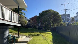 Un barrio residencial con césped, una valla de madera y casas al fondo.