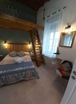 Un dormitorio con una cama, una escalera de madera, un escritorio y un espejo.