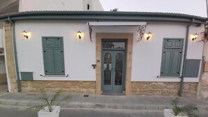 Ein Gebäude mit einer Stein-Fassade, einer grünen Tür und zwei Blumentöpfen am Eingang.