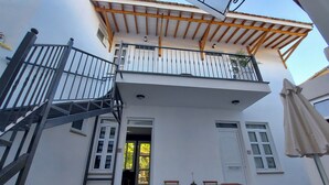 Ein zweistöckiges Gebäude mit Balkon, Treppe und Außenbereich zum Sitzen.