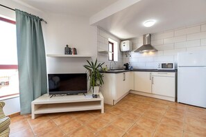 Uma cozinha moderna com armários brancos, forno embutido, micro-ondas e coifa de aço inoxidável.