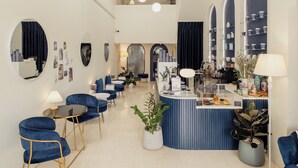 A modern interior with a reception desk, blue seating, and decorative mirrors. - Shapel Hostel and Cafe (Chiang Mai)