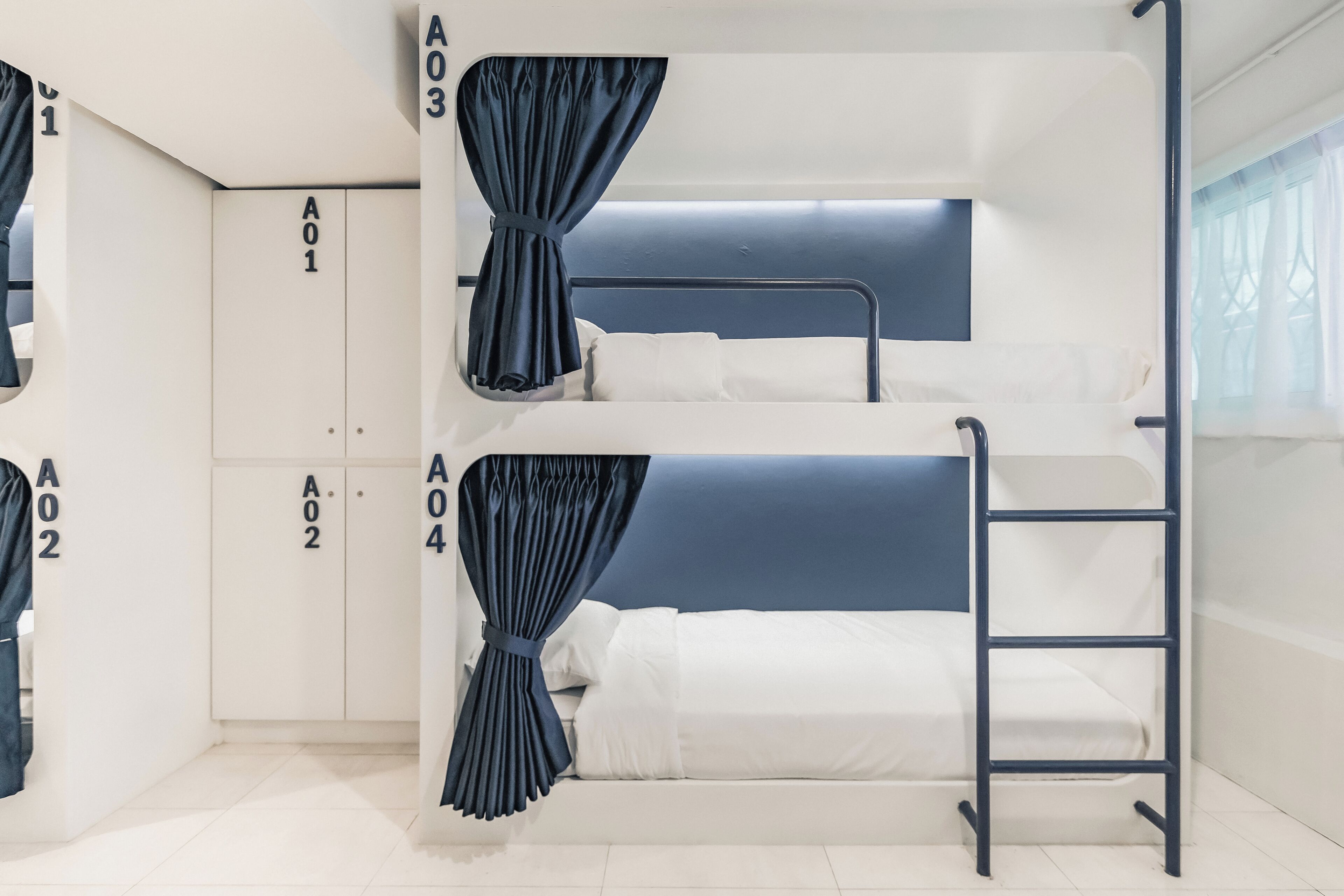 A bunk bed room with curtains, a wardrobe, and a ladder.