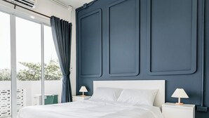 A modern bedroom with a large bed, two bedside tables with lamps, a dark accent wall, and a view through a sliding glass door. - Shapel Hostel and Cafe (Chiang Mai)