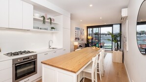 A modern kitchen with white cabinetry, a wooden countertop, and a built-in oven. There is a large window providing a view of the city.
